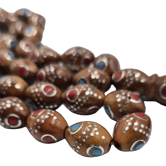 Carved from the resilient Narjil (Coconut) Shell, this tasbih combines organic warmth with metallic precision. Each bead is inlaid with striking Silver-Tone with Red and Blue Craftings.