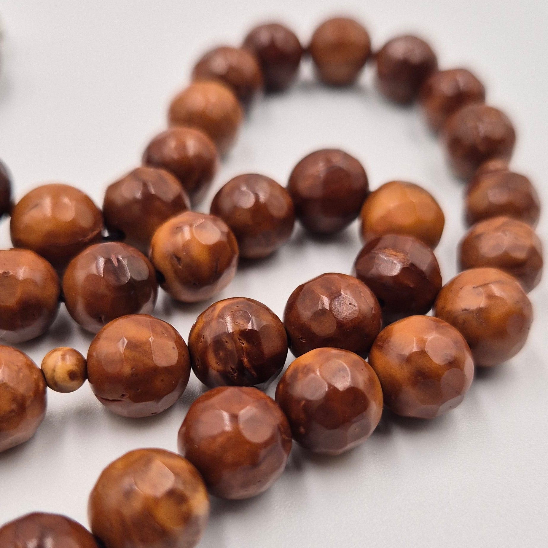 Carved from the resilient Narjil (Coconut) Shell, this tasbih combines organic warmth with metallic precision. Each bead is inlaid with striking Silver-Tone with Red and Blue Craftings.