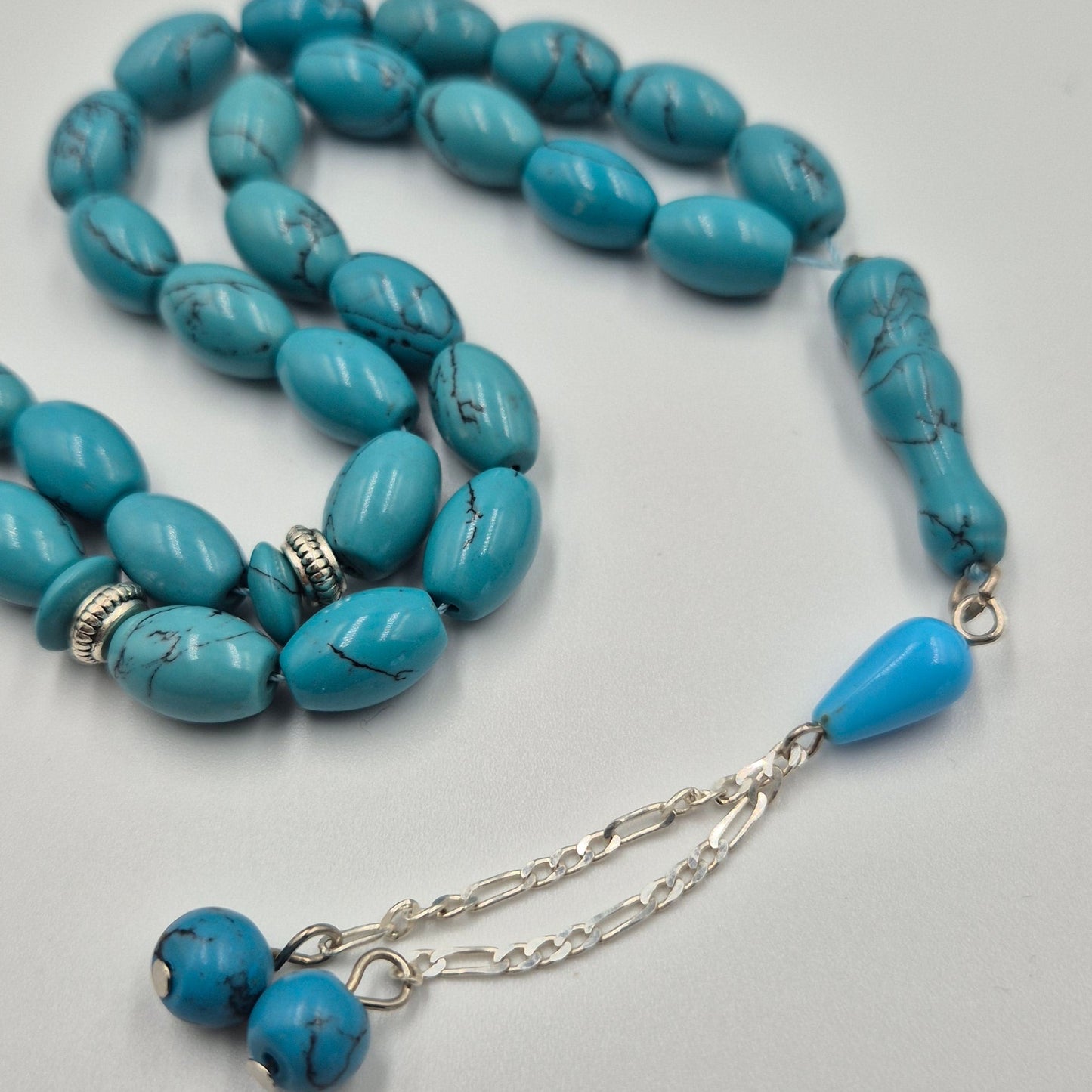 Turquoise beaded necklace with silver chain on a light gray background