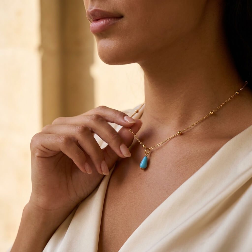Close-up of a Fairouz teardrop drop held between the fingers, silver gold-plated satellite chain — gift for her UAE