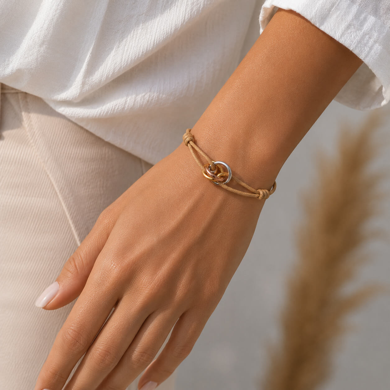 Trilogy Three-Ring adjustable cord bracelet, on the wrist beside the cuff — fashion accessory Dubai