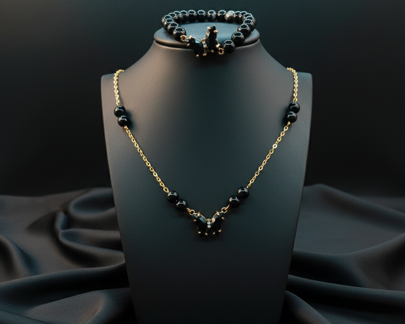 Black beaded necklace and bracelet set on a black mannequin bust with a dark fabric background