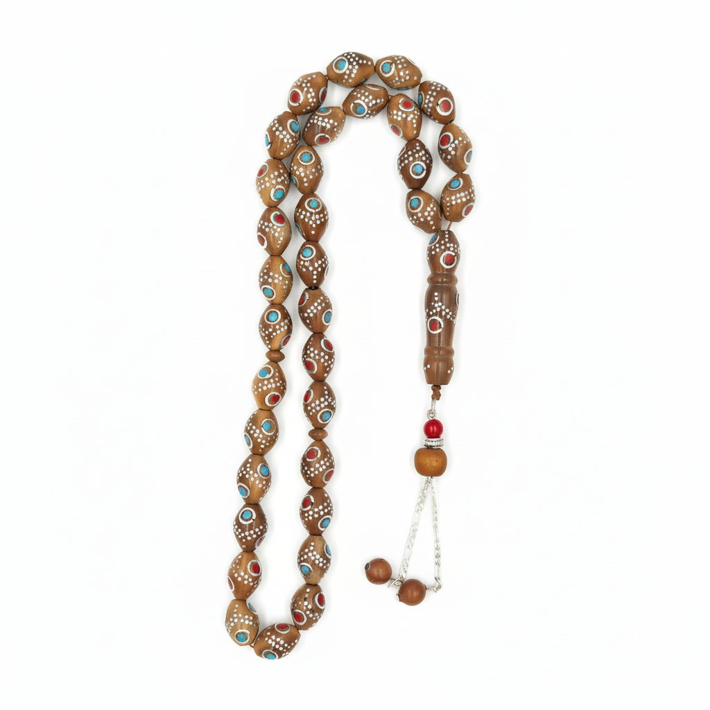 Carved from the resilient Narjil (Coconut) Shell, this tasbih combines organic warmth with metallic precision. Each bead is inlaid with striking Silver-Tone with Red and Blue Craftings.