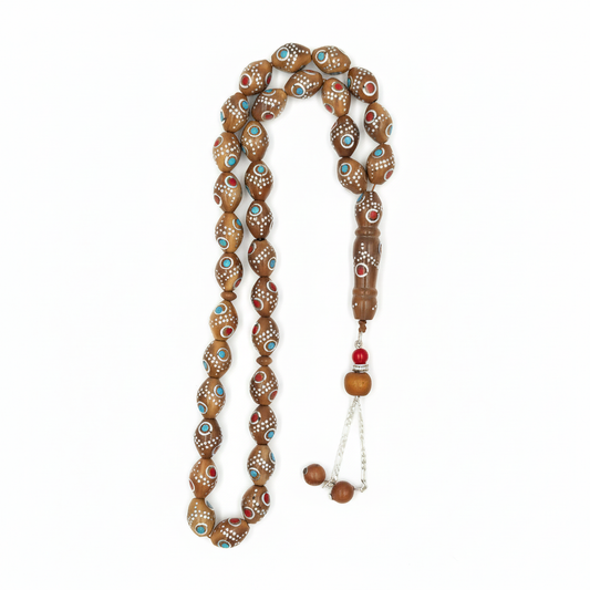 Carved from the resilient Narjil (Coconut) Shell, this tasbih combines organic warmth with metallic precision. Each bead is inlaid with striking Silver-Tone with Red and Blue Craftings.